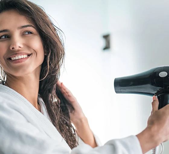 Wordt je verkouden door met nat haar naar buiten te gaan? Vrouw föhnt haar haar.